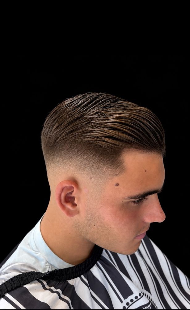 A low skin fade with a swept, textured top, cut at The Private Chair